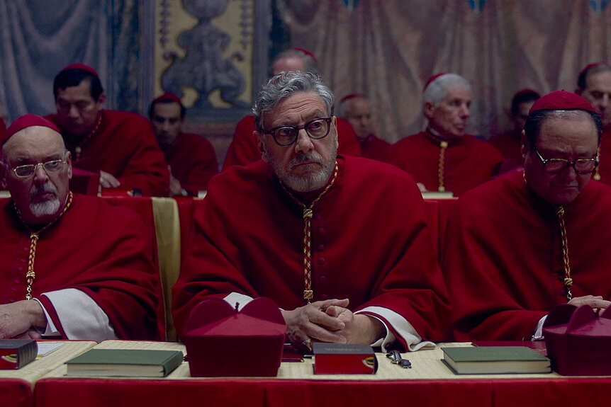 Cardinals wearing all red sitting at a table in the movie Conclave