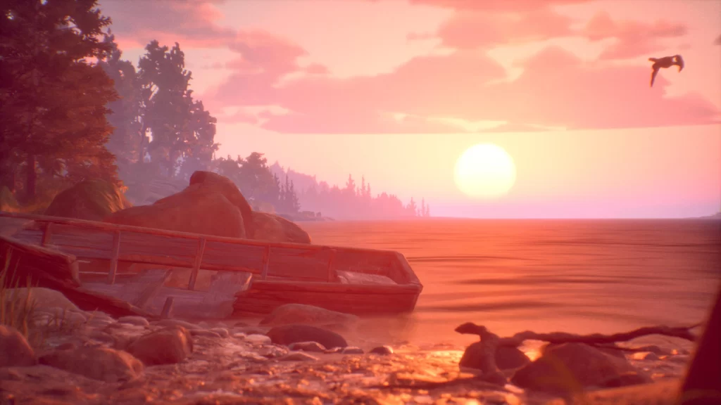 A sunset over a lake with an old boat washed up on the shore