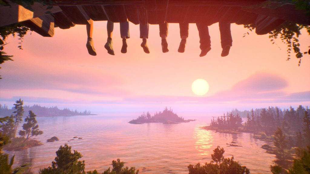 four pairs of legs hanging over a dock in front of a sunset.