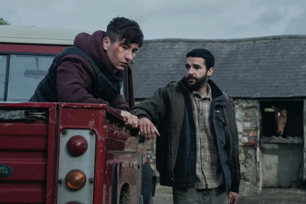 Two guys are in frame. One is in the back of a truck with blood on his face and the other is standing beside looking concerned.